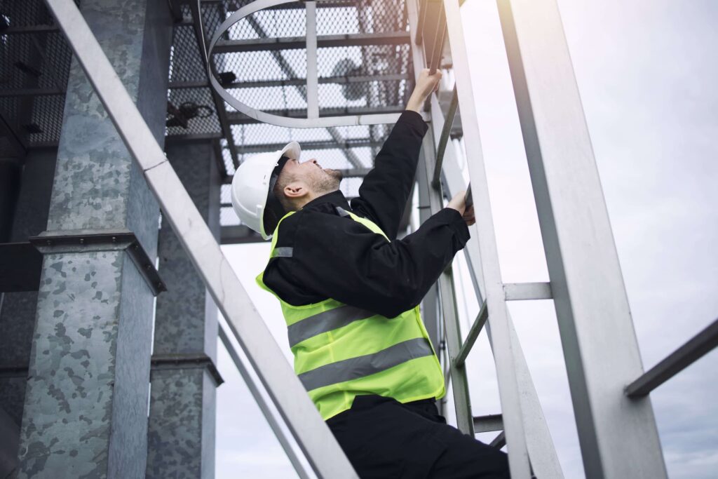Industrial factory construction worker climbing metal ladder of production plant