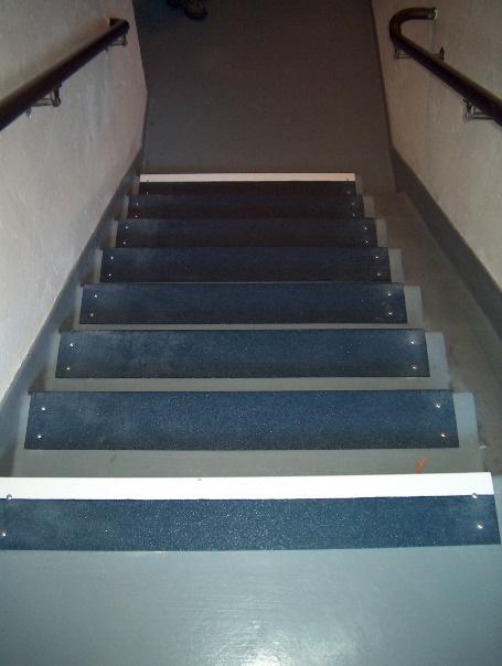Safeguard step covers used in a school stairwell with a white stripe on the leading edge of the top and bottom stairs