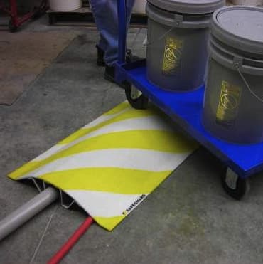 Yellow and white striped Pipe cable covers with cart being pushed over it