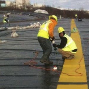 Workers installing roll traction while standing on yellow anti-slip