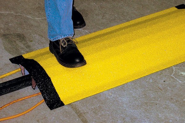 Yellow and black pipe and cable cover with person walking over it